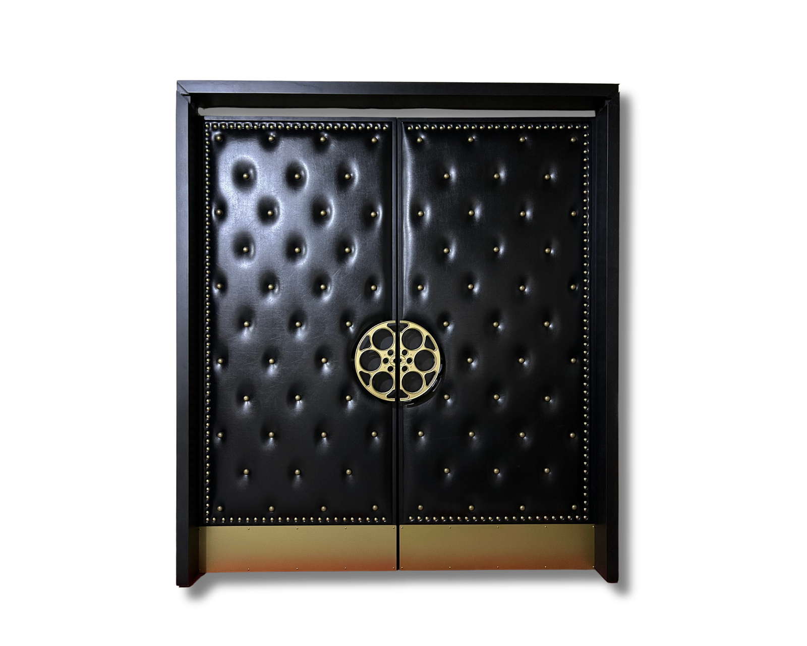 Ornate double cabinet or door panels with black tufted leather upholstery, brass nailhead trim, and a prominent gold film reel handle centered on the seam. The piece features a sleek black frame and a warm gold metallic base, set against a solid black background