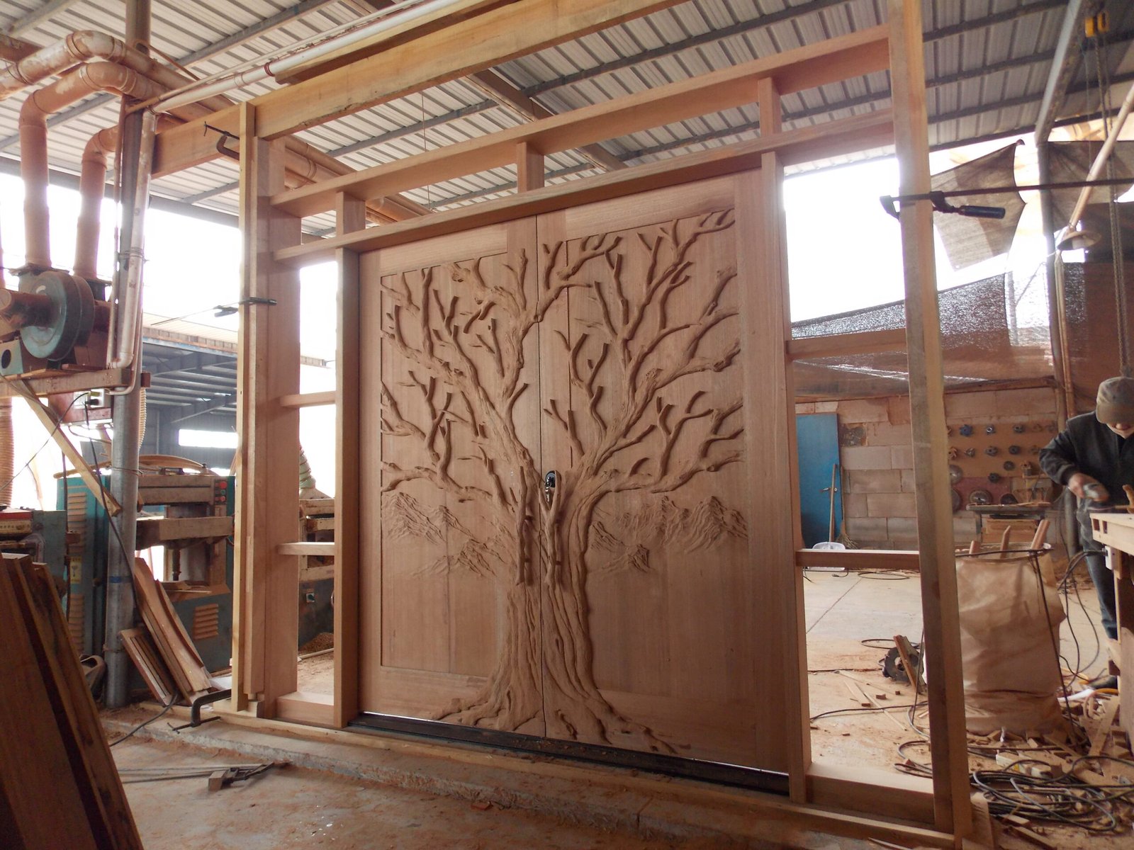 Full pre-assembly test of a hand-carved Tree of Life solid wood double door with sidelight and transom jamb frame inside the Crown Custom Doors manufacturing workshop.