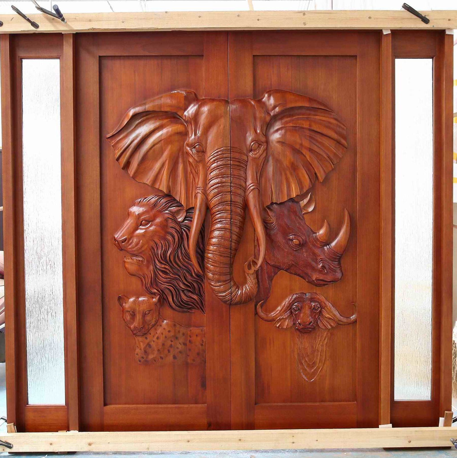 Front studio view of a pre-hung solid wood double entry door featuring hand-carved African Big Five wildlife—an elephant, lion, leopard, rhinoceros, and Cape buffalo—flanked by dual textured glass sidelights.