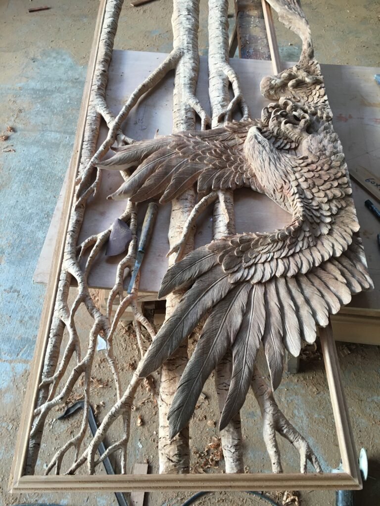 Full view of a hand-carved solid wood door panel layout showing a bald eagle in flight over intricate tree branch relief before final assembly.