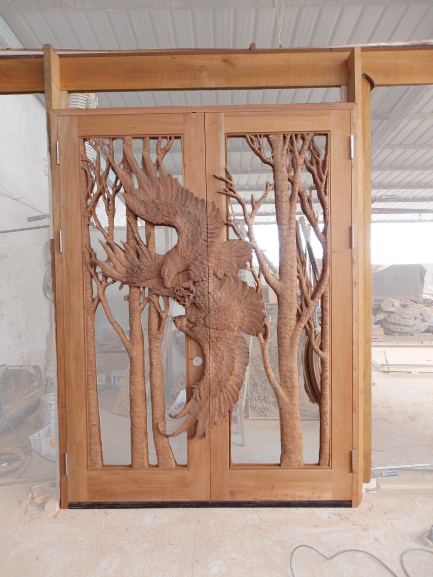 Front view of a fully assembled pre-hung solid wood double entry door featuring a seamless hand-carved eagle in flight across both door panels.