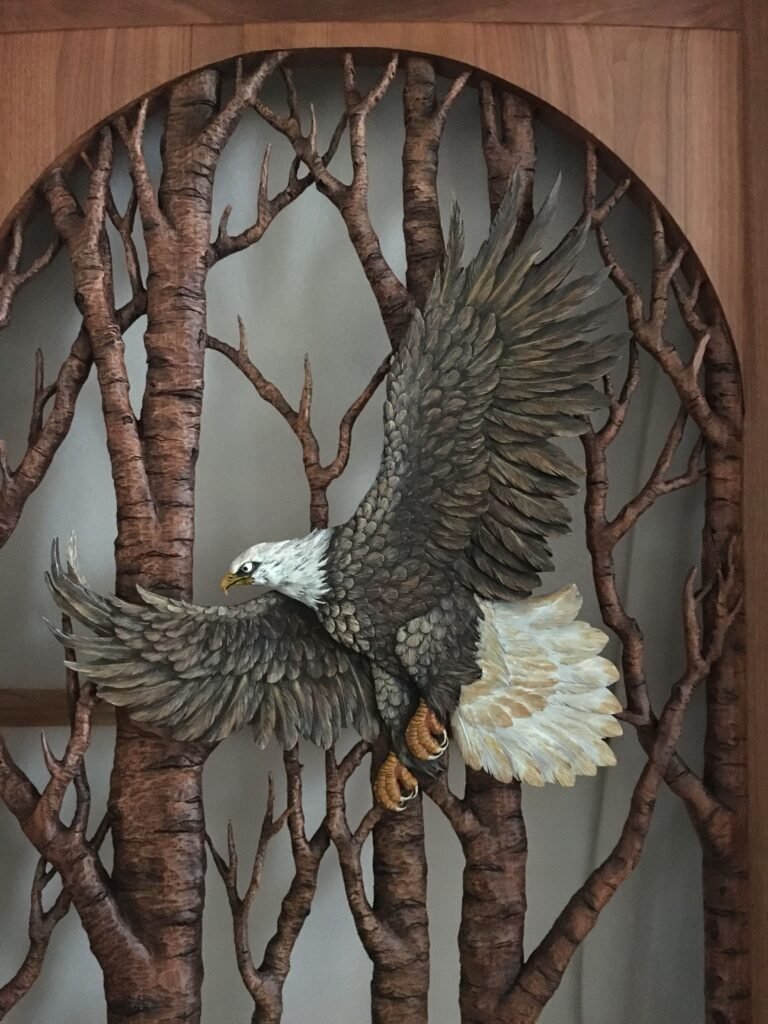 Fully hand-carved and hand-painted solid mahogany bald eagle soaring through birch trees framed within an arched door insert panel.