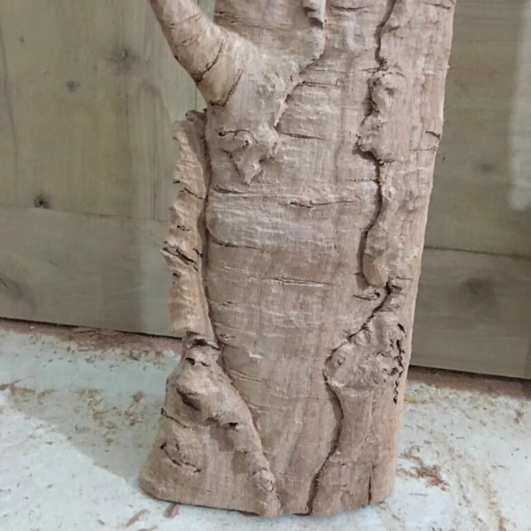 Close-up detail of hand-carved solid mahogany wood casing sculpted with realistic peeling birch tree bark texture for a custom front door frame.