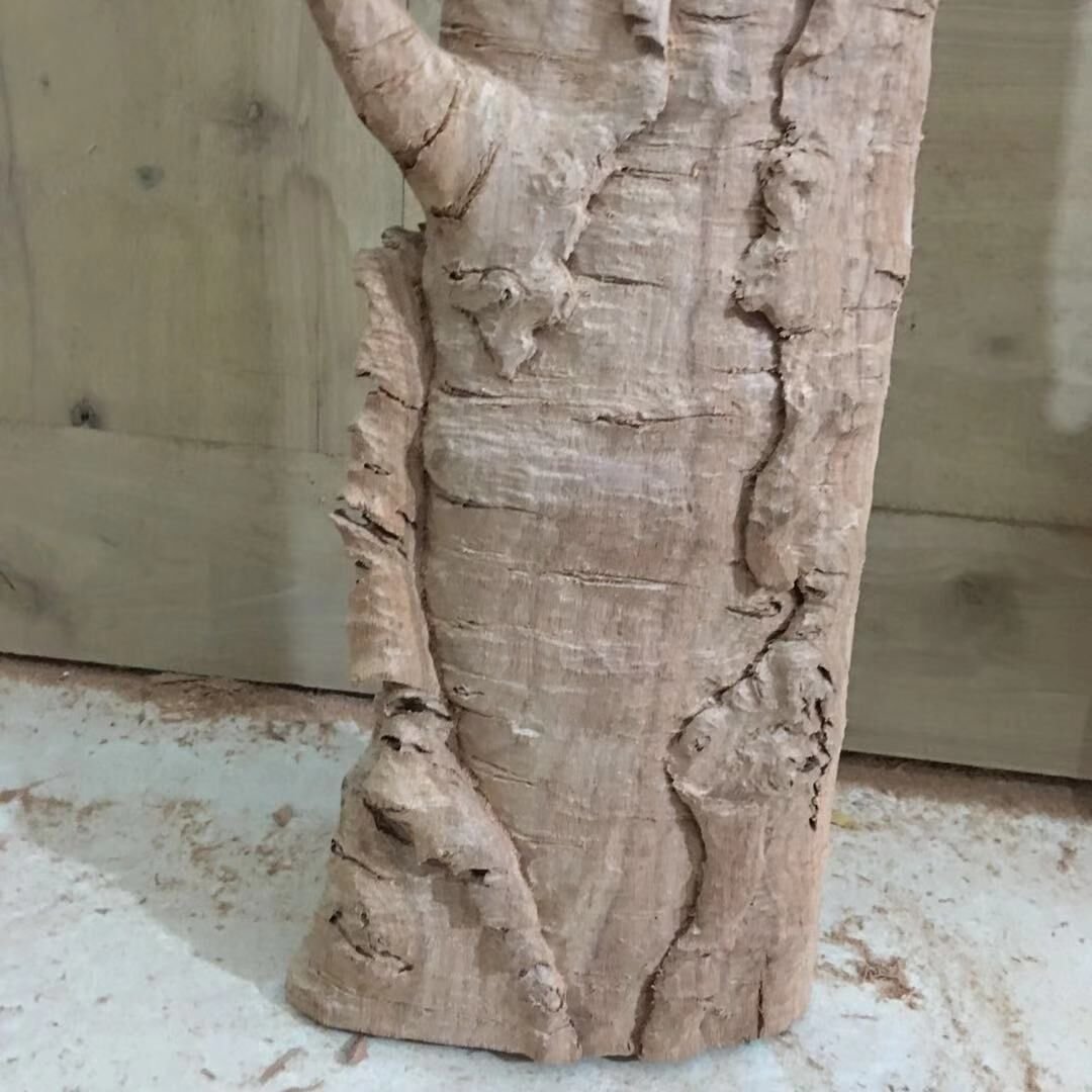 Close-up detail of hand-carved solid mahogany wood casing sculpted with realistic peeling birch tree bark texture for a custom front door frame.