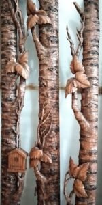 Close-up detail of hand-carved solid mahogany tree bark casing with sculpted leaves, branches, and a miniature wood birdhouse for a front door frame.