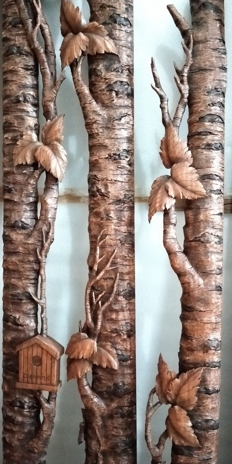 Close-up detail of hand-carved solid mahogany tree bark casing with sculpted leaves, branches, and a miniature wood birdhouse for a front door frame.