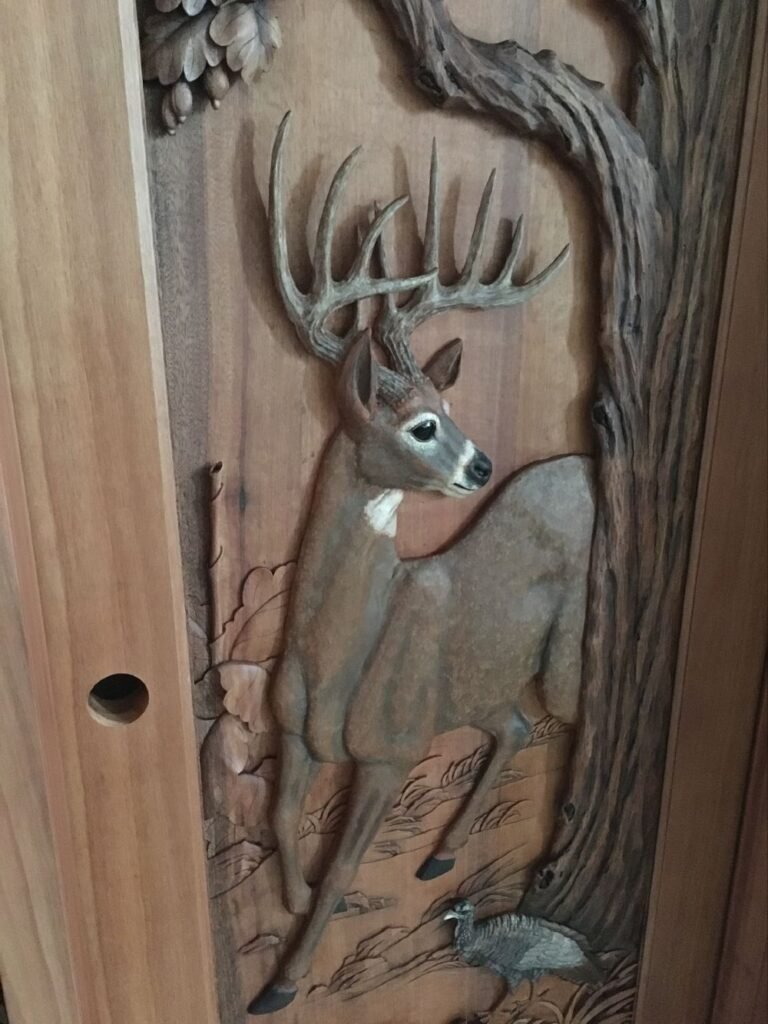Vertical view of a solid wood door panel featuring a hand-carved and hand-painted trophy buck deer standing next to an oak tree with a wild turkey at the base.
