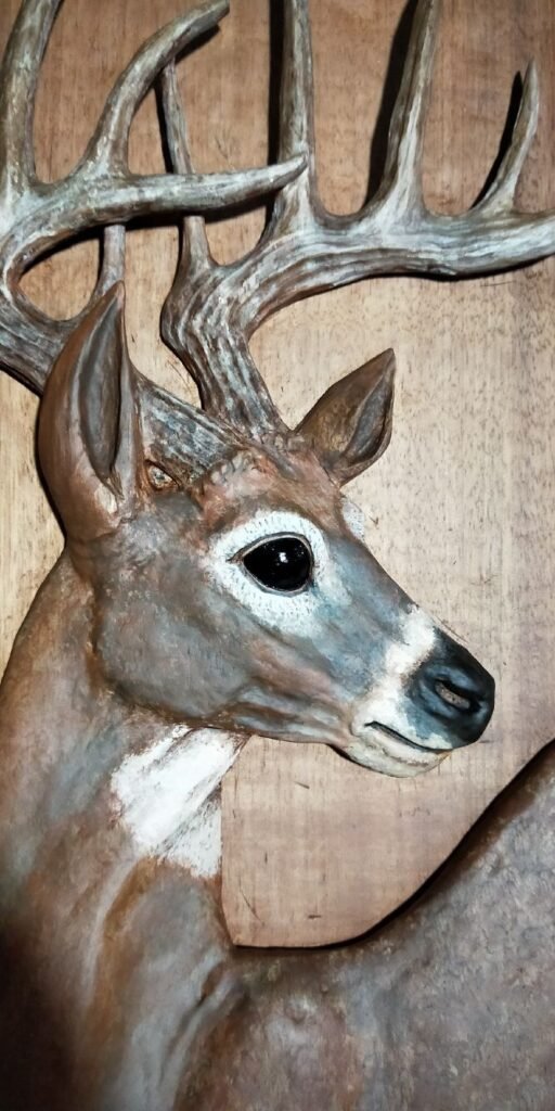 Close-up view of a hand-carved and realistic hand-painted trophy buck deer head with textured antlers on a solid wood door panel.