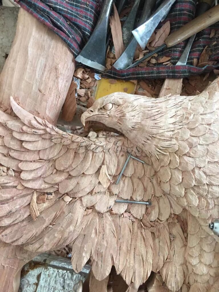 Close-up view of traditional woodcarving chisels and hand-carved solid wood bald eagle feathers in progress for a custom front door.