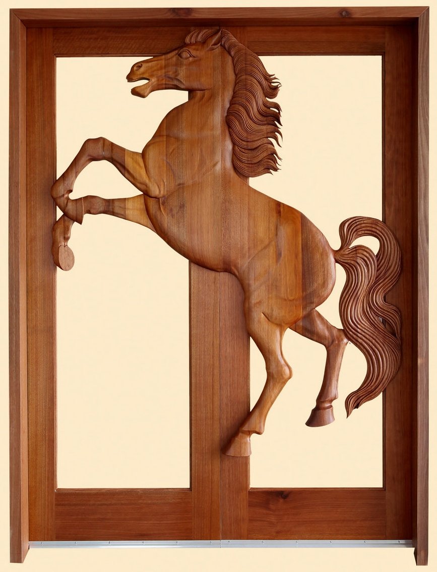 A front view of a finished, stained solid wood double entry door featuring a massive 3D hand-carved sculpture of a rearing wild horse with a detailed mane and tail seamlessly spanning across the central meeting stiles of an open glass-ready frame.