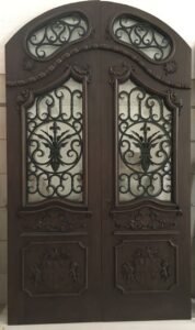 Bespoke Renaissance-inspired arched double entry door handcrafted from dark solid wood, featuring custom-carved coat of arms panels, exquisite baroque moldings, and hand-forged wrought iron grilles over glass panels.