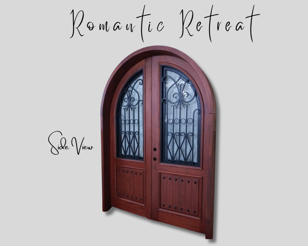 A side angle view of the "Romantic Retreat" custom arched double entry door handcrafted from warm solid mahogany wood, featuring rustic plank lower panels with black decorative clavos and arched glass window inserts protected by hand-forged black wrought iron scrollwork.