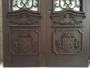 Symmetrical front view of the lower panels of a solid wood double entry door, featuring matching, highly detailed hand-carved family crests with heraldic dragons and unicorns beneath decorative baroque scrollwork cartouches.
