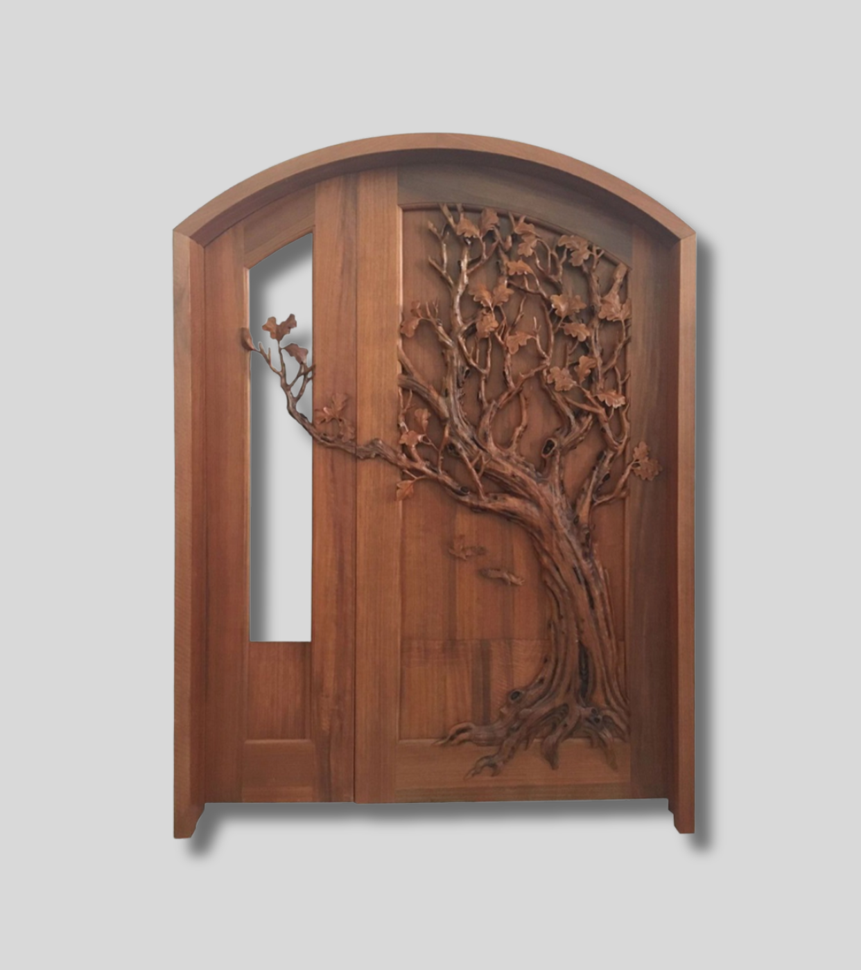 Crown Custom Doors studio view of an arched solid wood double door featuring high-relief carvings of a spreading oak tree and an asymmetrical vertical glass panel insert.