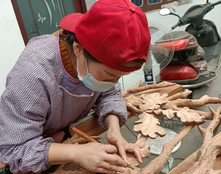 Master woodcarver using traditional hand tools to shape oak leaf relief details on a solid wood door panel.