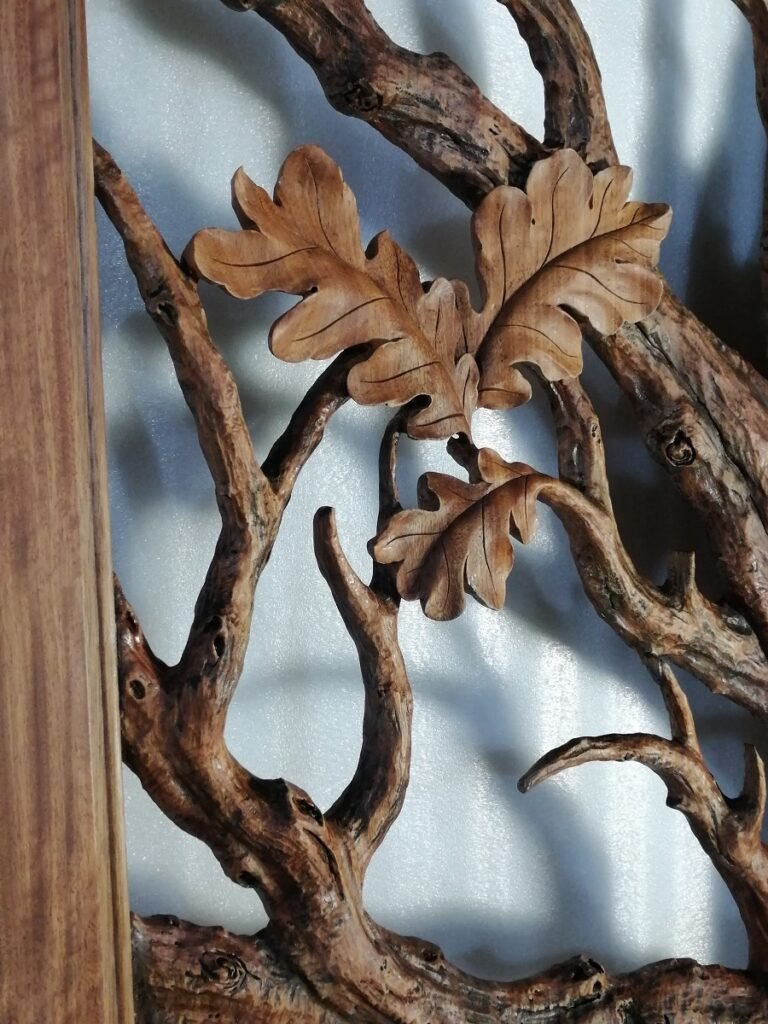 Vertical close-up of finished solid wood entry door featuring sculpted oak leaf cluster and textured branch canopy near the door frame.