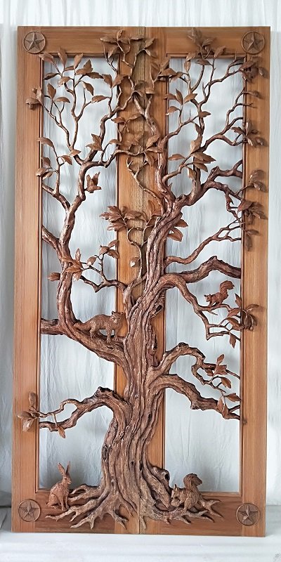 Studio view of handcrafted solid wood double doors featuring a high-relief 3D carving of a Texas oak tree with carved wildlife details including a raccoon, squirrels, and a jackrabbit, framed by carved Texas star corner rosettes.