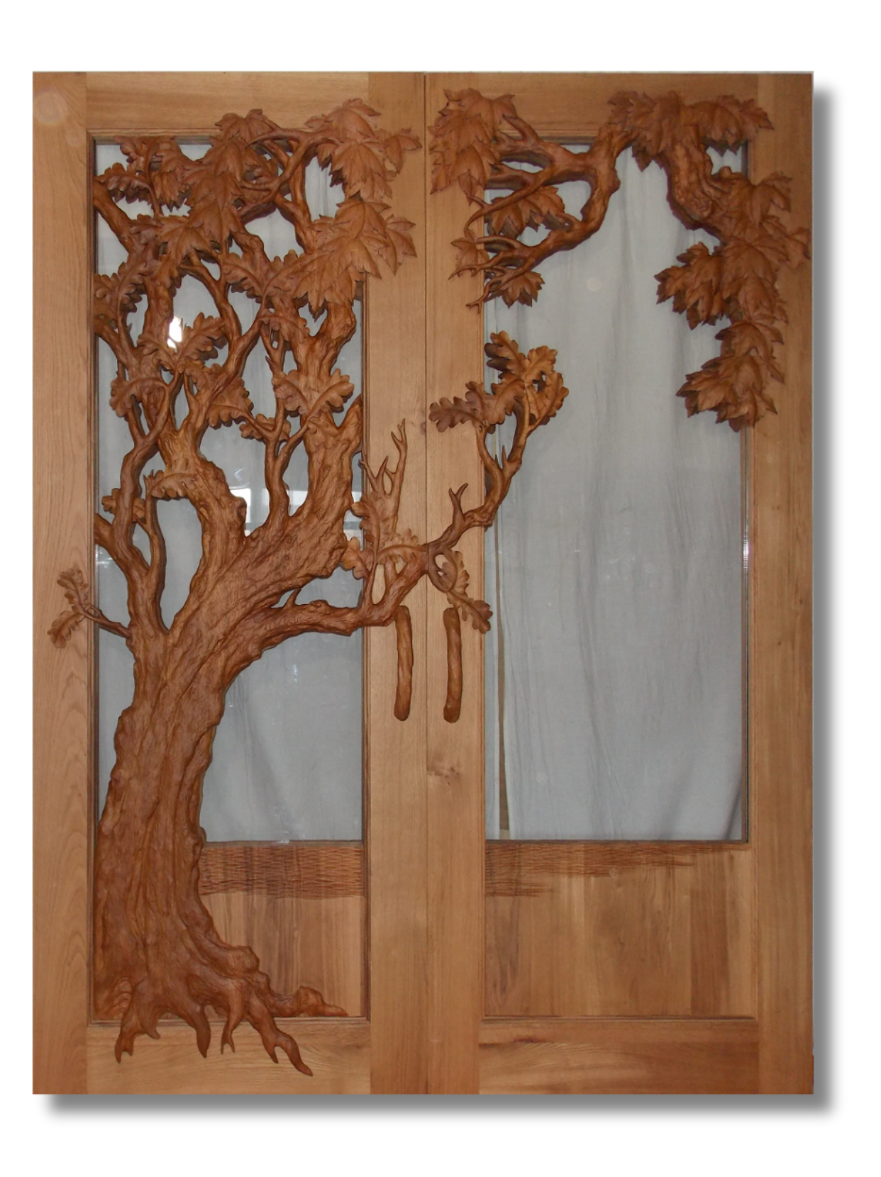 Studio view of handcrafted solid wood double entry doors featuring a 3D hand-carved oak tree with leaf clusters and branches spreading across clear glass inserts, complete with matching carved wood door handles.