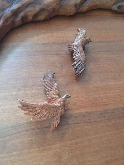 Crown Custom Doors high-relief close-up view of two hand-carved solid wood birds in flight with detailed feather carving on a custom entryway door.