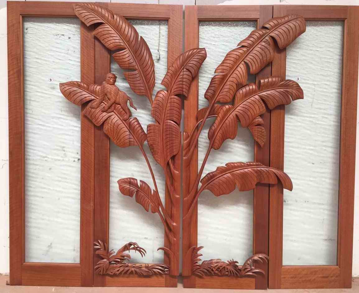Crown Custom Doors completed solid wood double entry door system featuring intricate relief carvings of tropical banana leaves and a monkey against glass panels.
