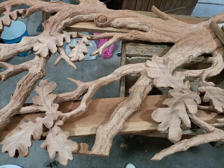 Unfinished solid wood hand-carved oak tree sculpture showing full branch network, leaf clusters, and natural bark texturing laid out on workshop floor.