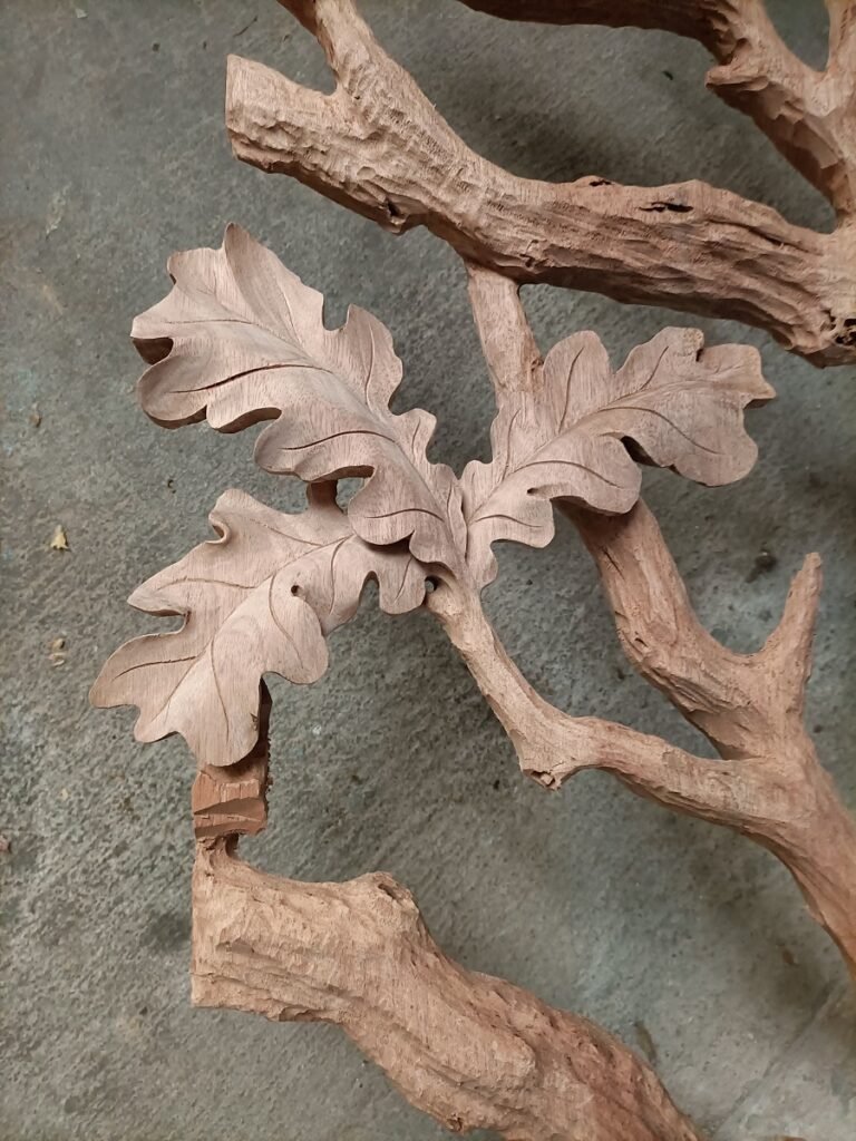 Extreme close-up of three-dimensional hand-carved oak leaves with fine vein textures and branch relief on solid wood.