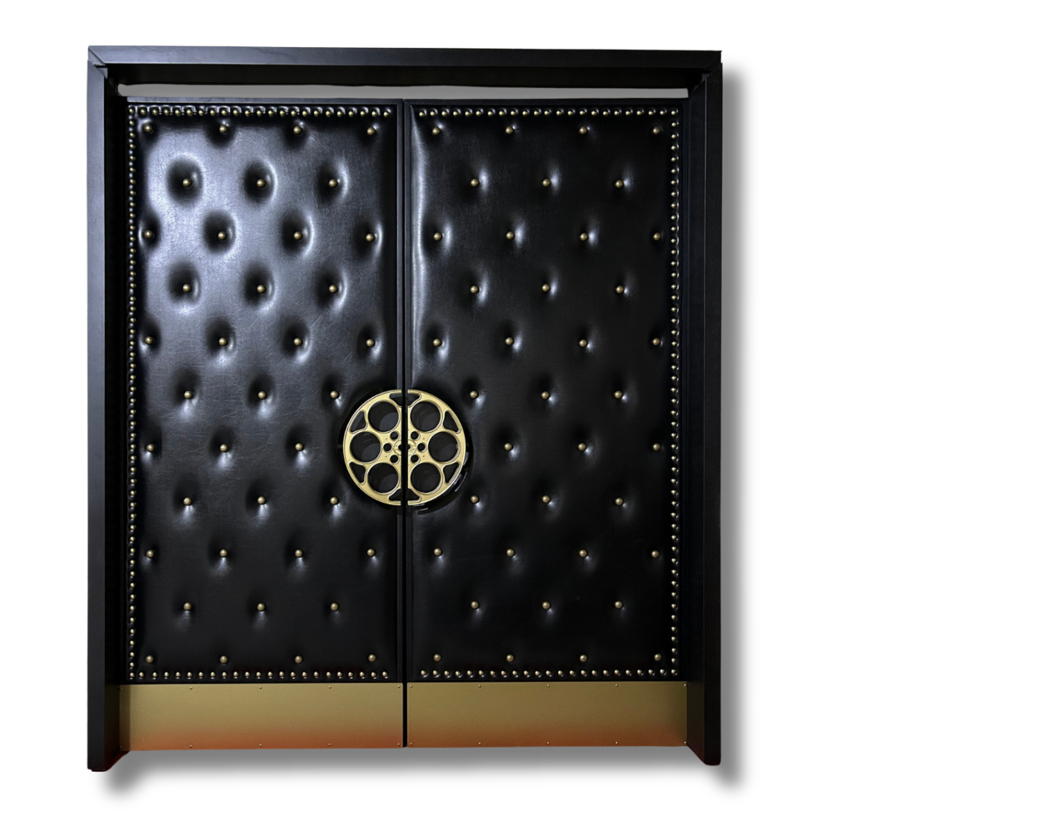 Custom black button-tufted vinyl acoustic home theater double doors featuring brass nailhead trim along the perimeter, a solid brass circular film reel center handle, and brass kickplates.