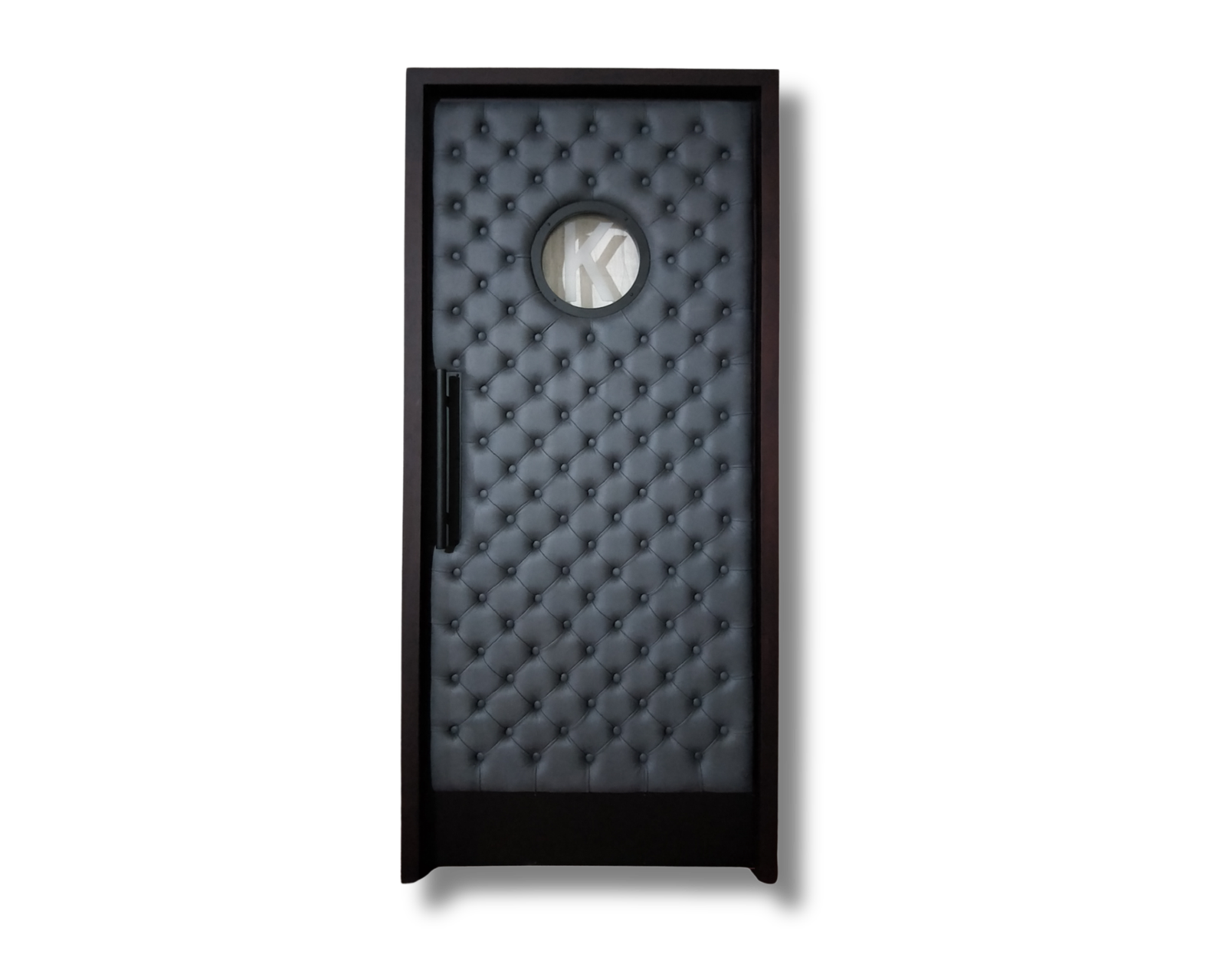 Studio product view of the James Kimber Theater custom acoustic home cinema door featuring charcoal black diamond-tufted leather upholstery, dark frame, circular porthole vision window, and matte black vertical pull handle.