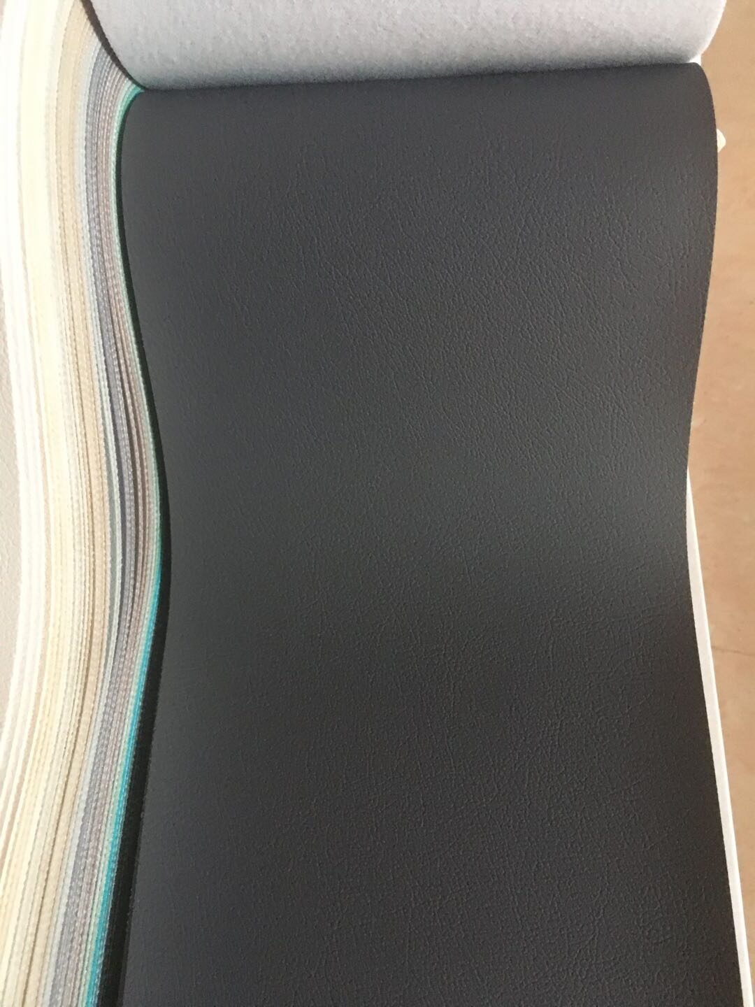 Textured storm gray faux leather upholstery vinyl swatch with plush felt backing for custom upholstered home theater doors by Crown Custom Doors.