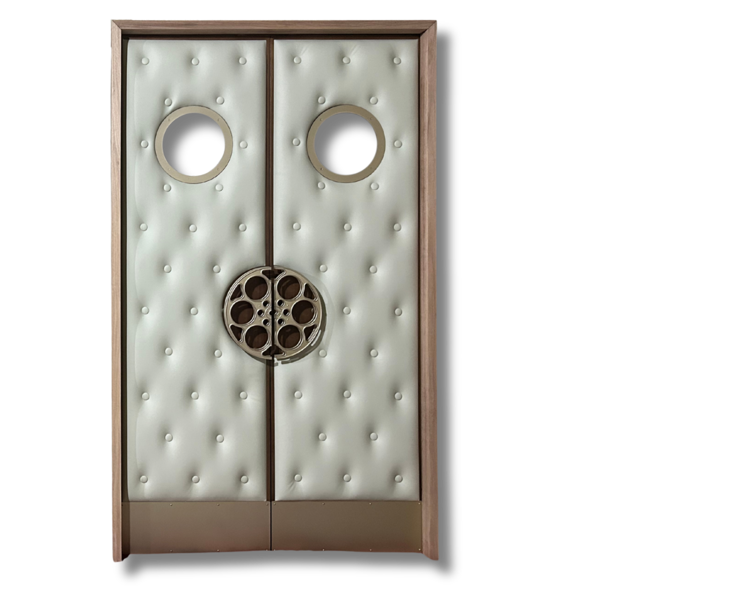 Custom off-white button-tufted vinyl acoustic home theater double doors featuring twin porthole windows, custom full-circle film reel center pull handles, and bottom kickplates set in a wooden jamb frame.