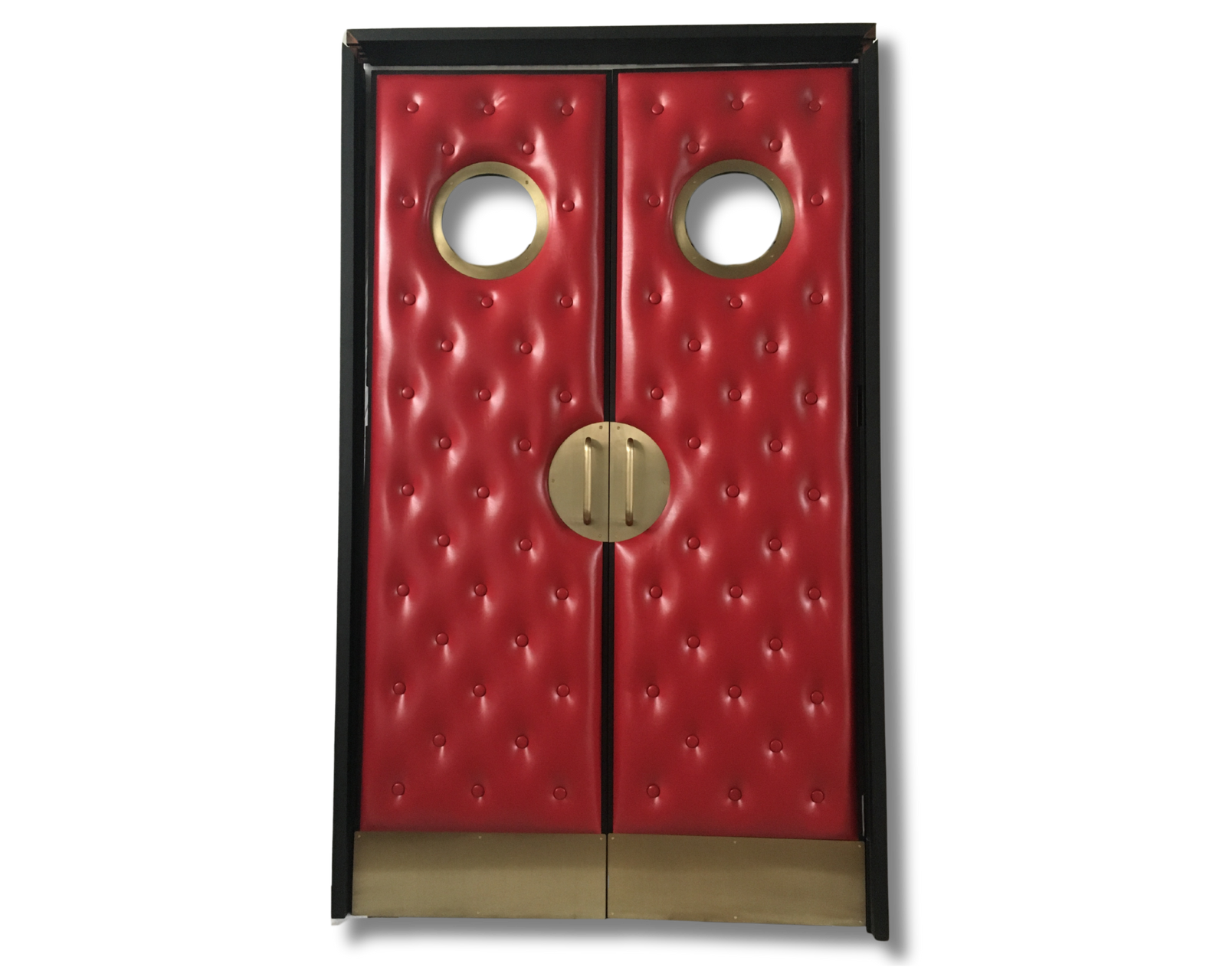 Front view of custom red vinyl diamond-tufted acoustic home theater double doors isolated on a black background, featuring brass porthole vision windows, round brass handles, and kick plates by Crown Custom Doors.
