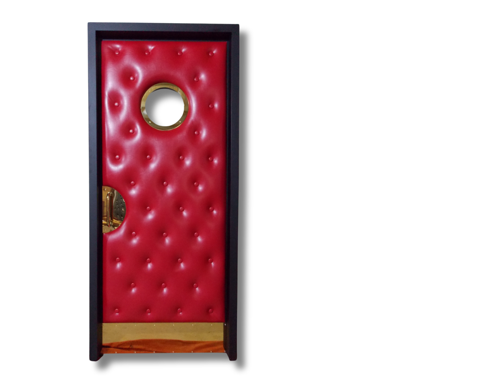 Custom wine red tufted upholstered home theater door featuring a round brass porthole window, brass kick plate, and brass half-moon handle inset in a dark wood frame.