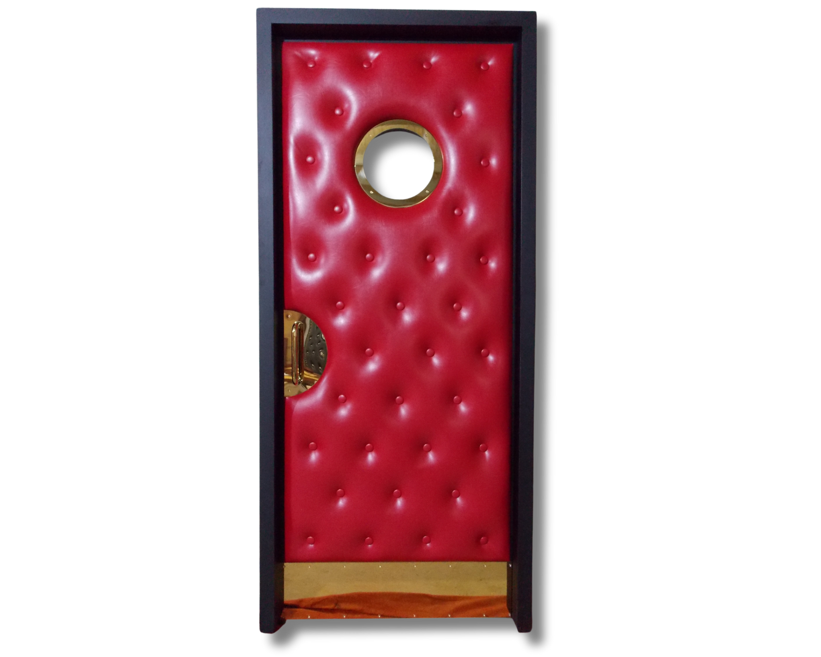 Custom wine red tufted upholstered home theater door featuring a round brass porthole window, brass kick plate, and brass half-moon handle inset in a dark wood frame.